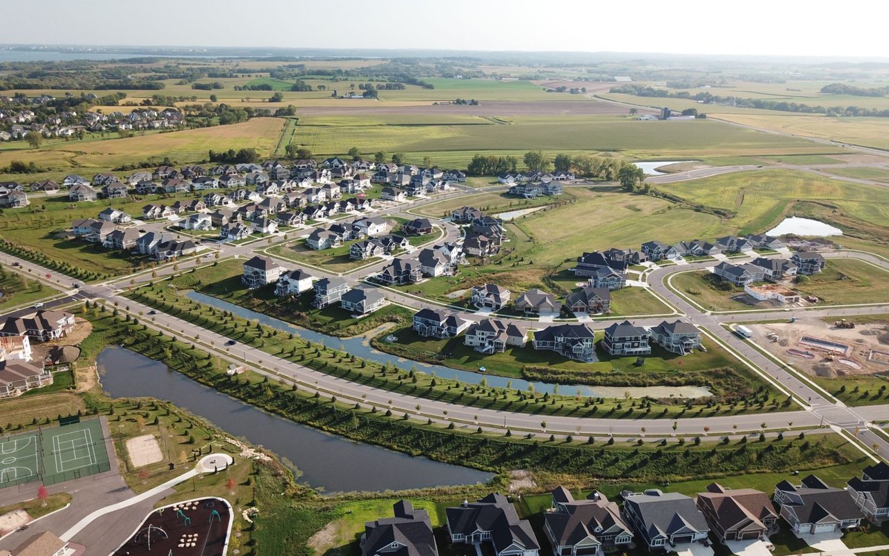 Aerial view of a residential area with several single-family homes, parks, playgrounds, and green spaces.