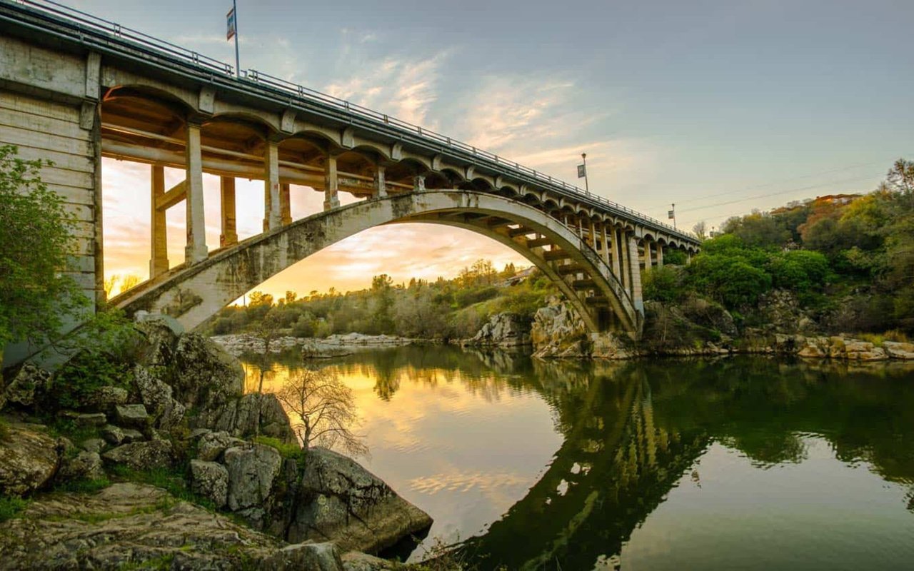 a red suspension bridge, the Rainbow Bridge, at sunset.