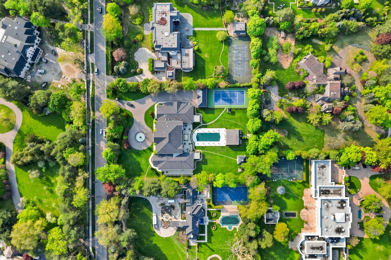  An aerial top-down view of a luxurious residential neighborhood with sprawling properties and abundant green spaces.