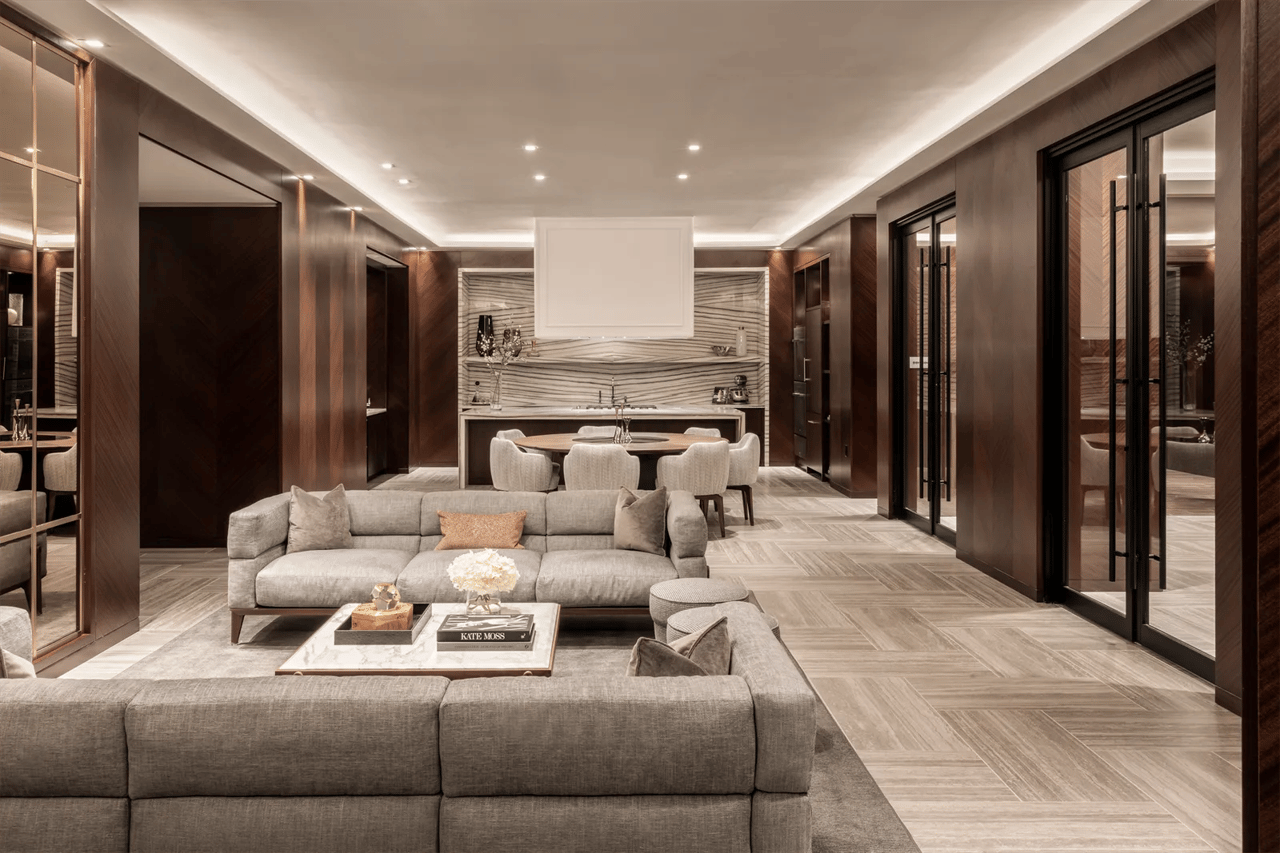 Living and dining area with gray sofas, a round table, and a veined marble feature wall.