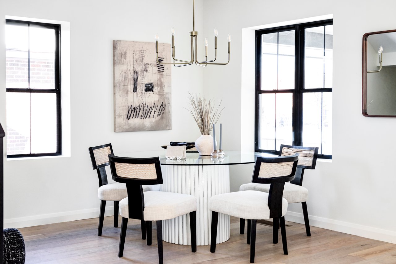 Close up shot of circular dining room table with 5 plush white chairs and modern artwork