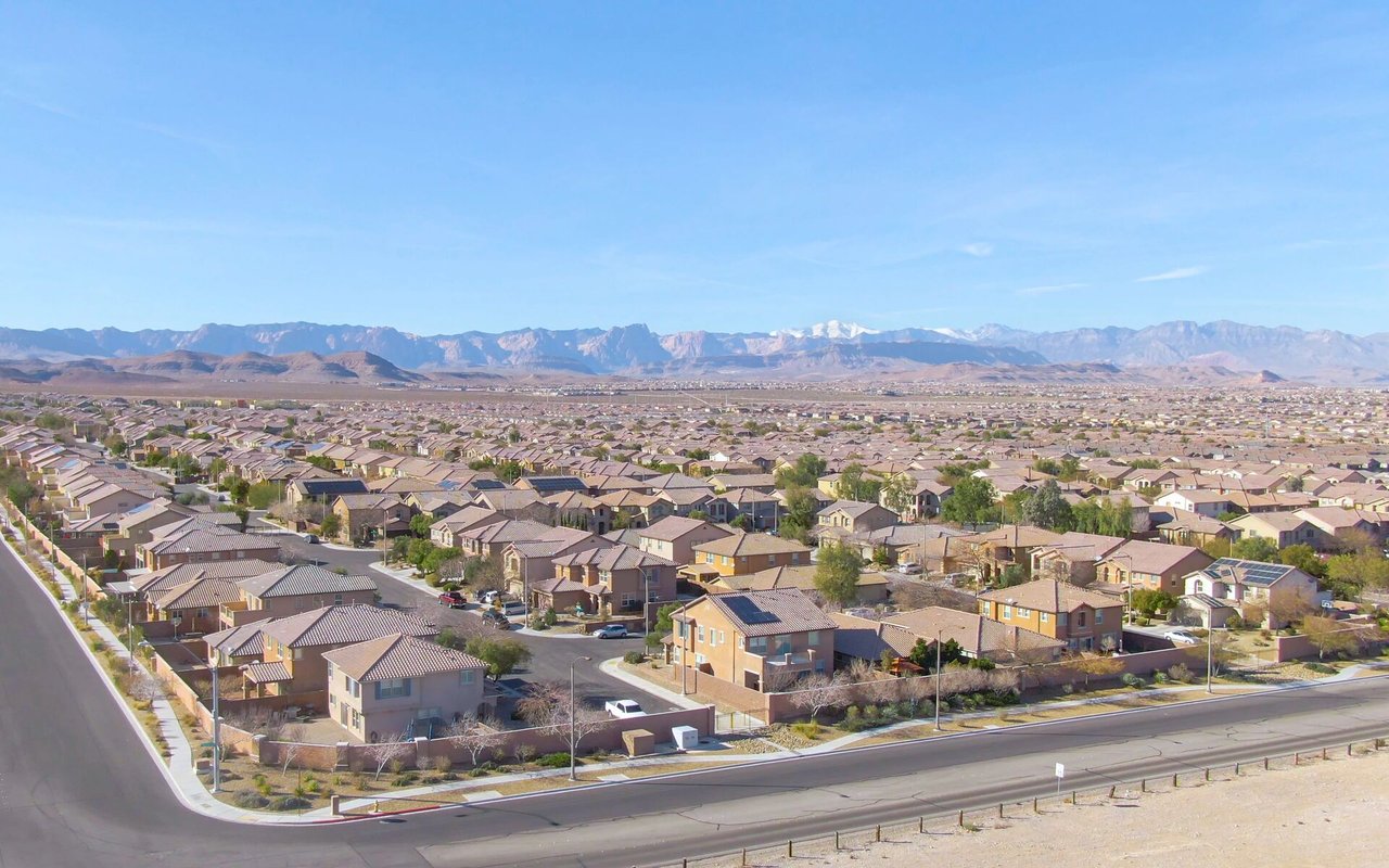 Aerial view of a residential valley neighborhood with mountains on the horizon.