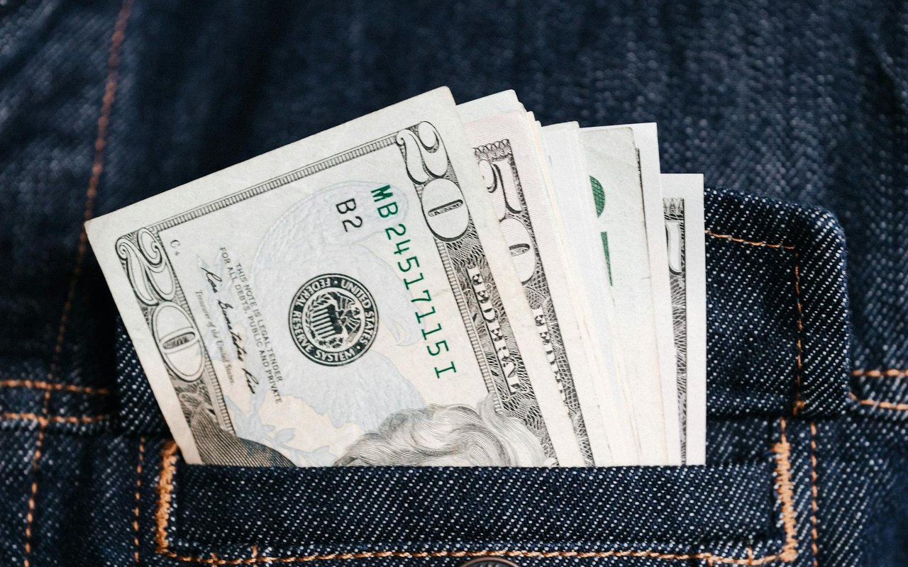 U.S. dollar bills tucked into a dark denim jeans pocket.