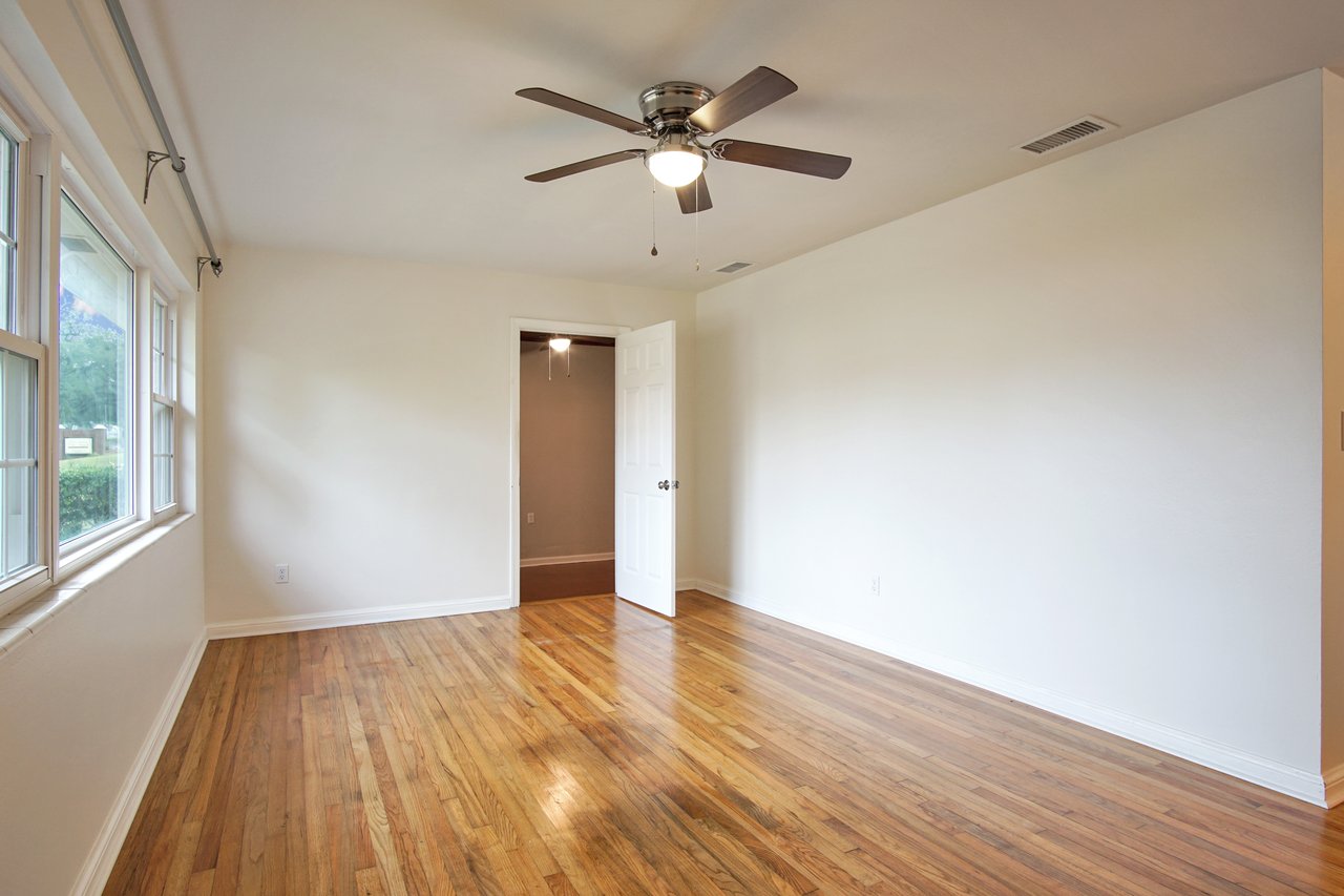 A room featuring hardwood floors and a ceiling fan for ventilation.