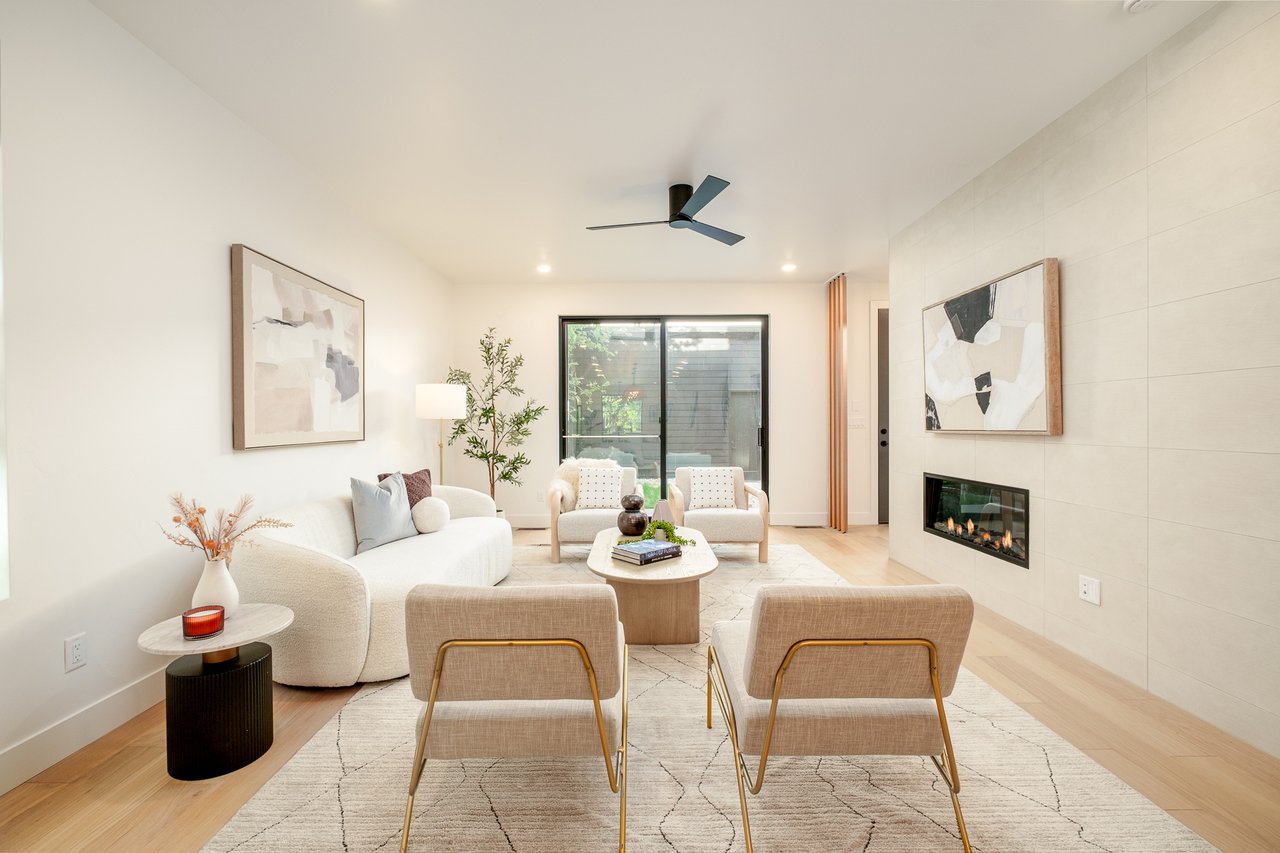 Staged living room with cream seating, a tiled fireplace wall, and sliding glass doors.