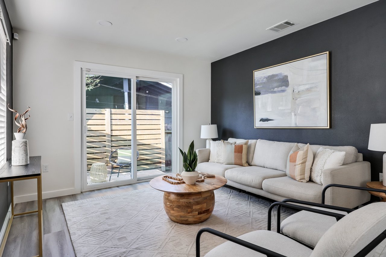 Living room with a white sectional, round wooden coffee table, and sliding glass doors to a patio.