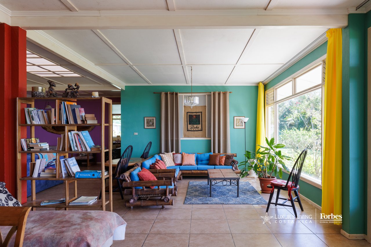 Living room with colorful seating, turquoise walls, and wide garden-facing windows.
