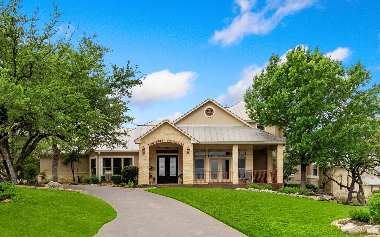 Mission Valley home with a stone facade, covered porch, mature trees, and curved driveway.