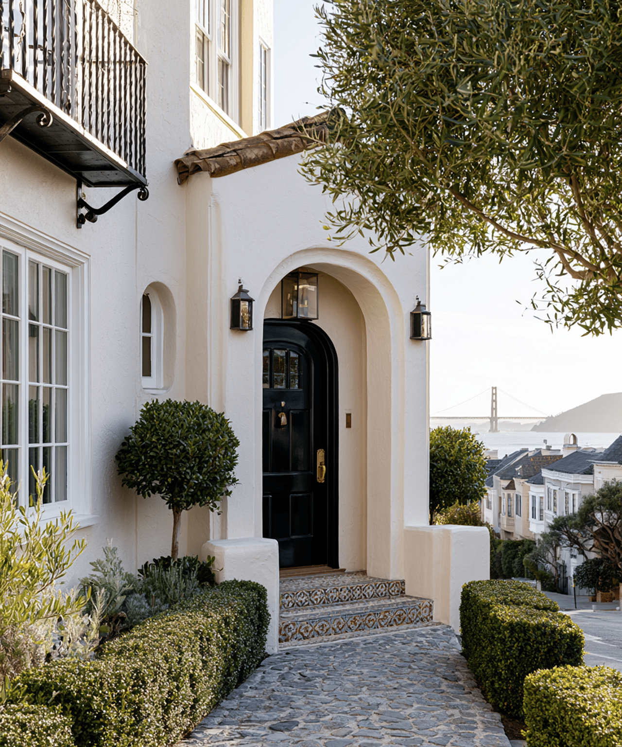 White stucco home with an arched entry and tiled steps, overlooking San Francisco rooftops and the bay.