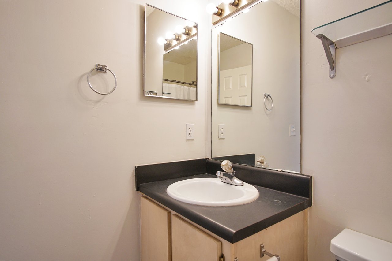 A clean bathroom featuring a modern sink and a large mirror reflecting the bright, well-lit space.