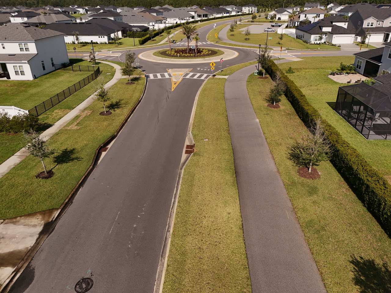 Aerial view of a neighborhood centered on a landscaped roundabout and curving street.