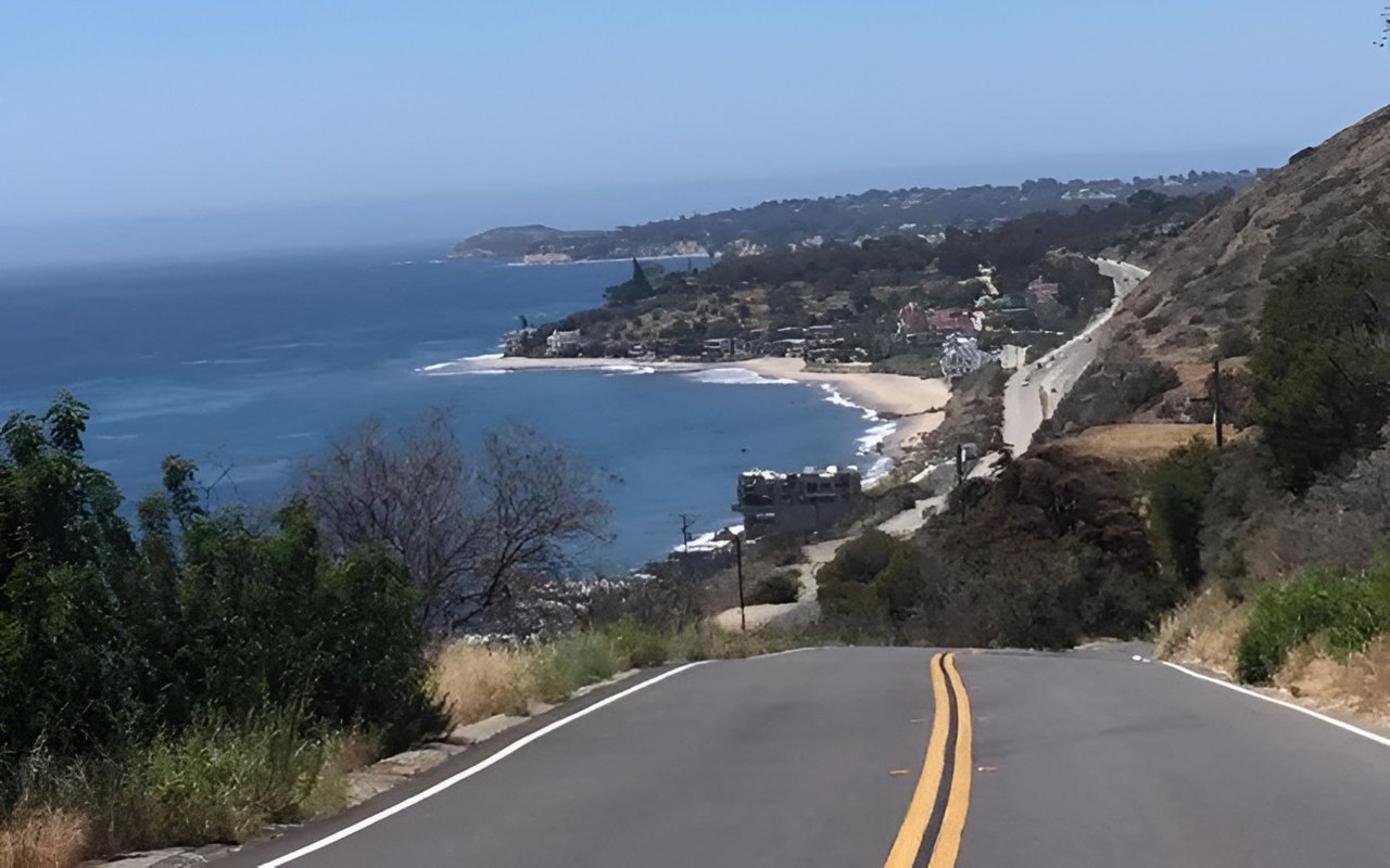 Malibu coastline seen from a winding hillside road above ocean coves and sandy beaches.