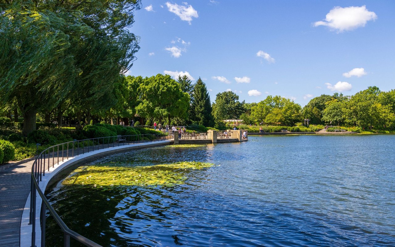 Lakeside park in Lake Forest with a curving walkway, viewing pier, and leafy trees.