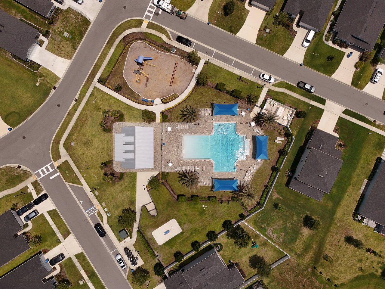 Community pool and playground surrounded by homes, viewed from above.