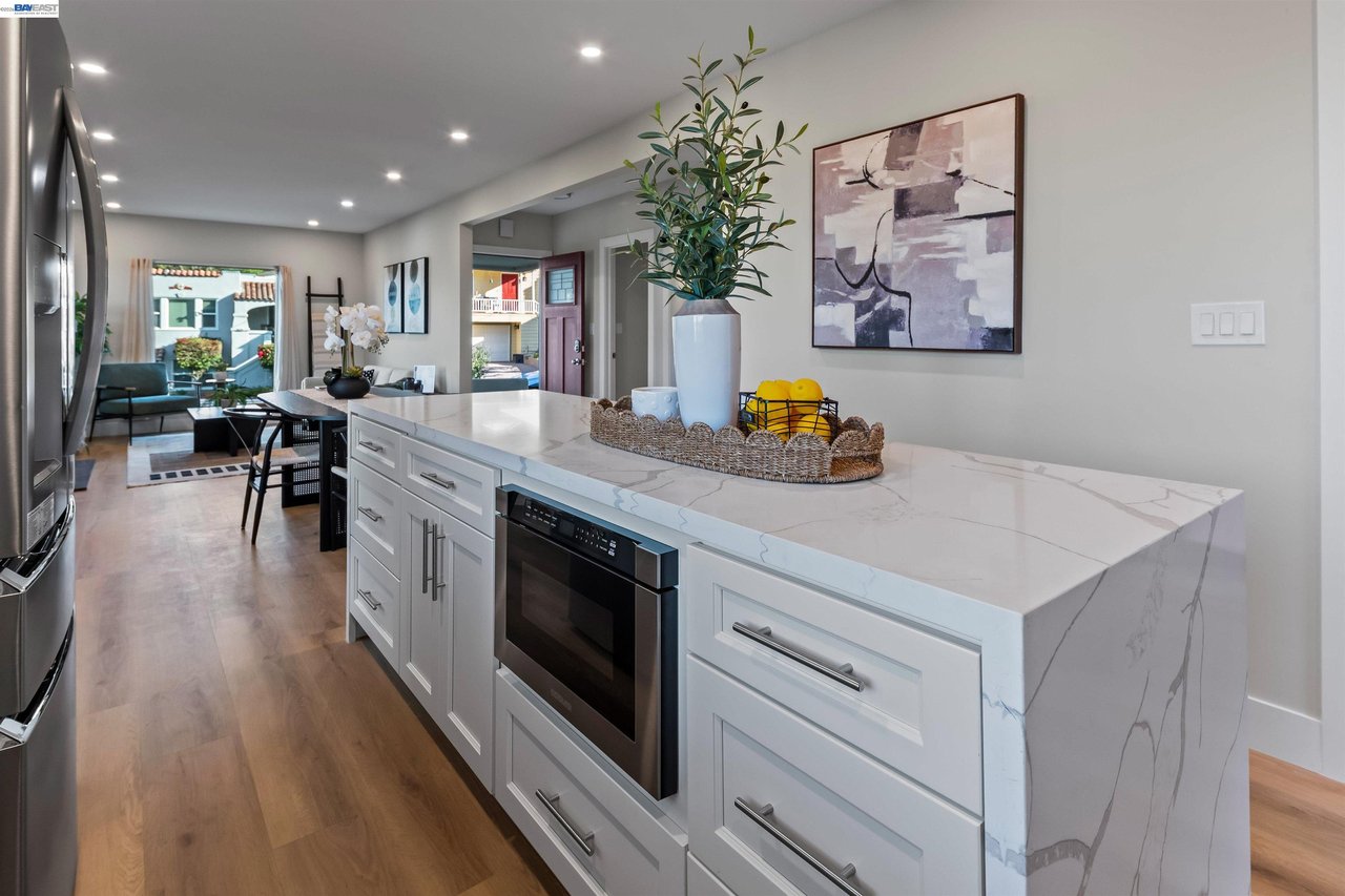 Staged kitchen with a marble-look waterfall island, white cabinets, and stainless steel appliances.