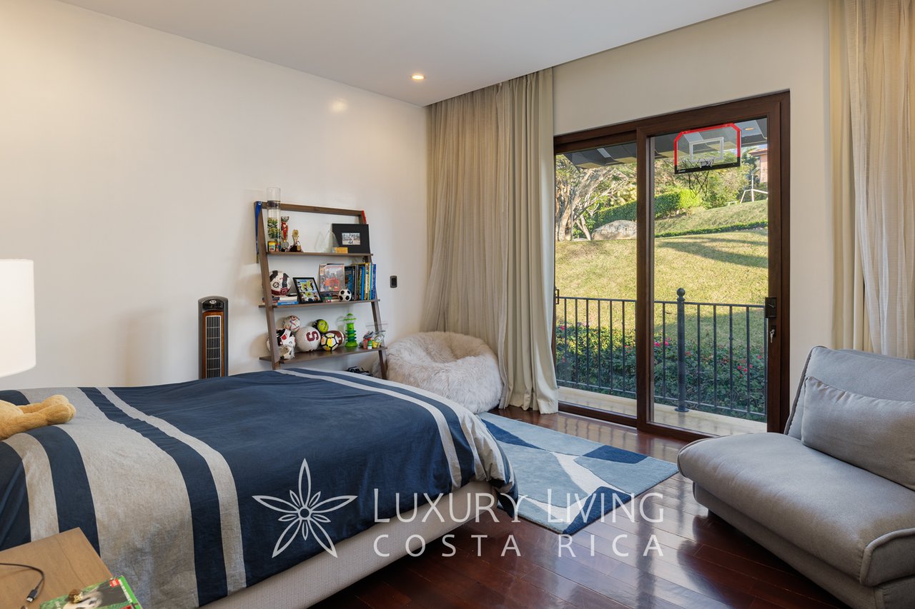Bedroom with navy-and-white bedding, a display shelf, and sliding glass doors opening to a balcony.