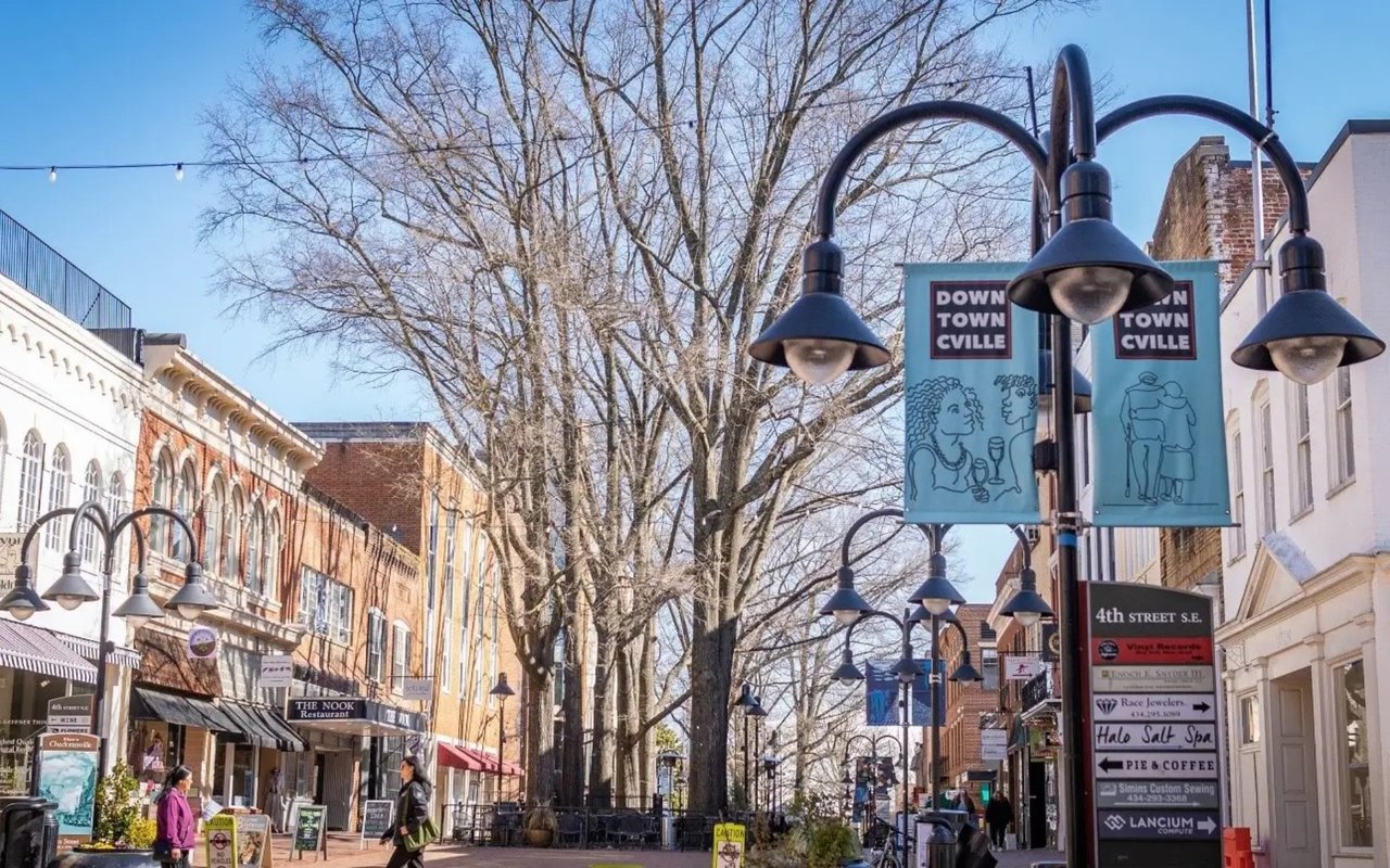 Downtown Charlottesville streetscape with historic storefronts, leafless trees, and Downtown Cville banners.