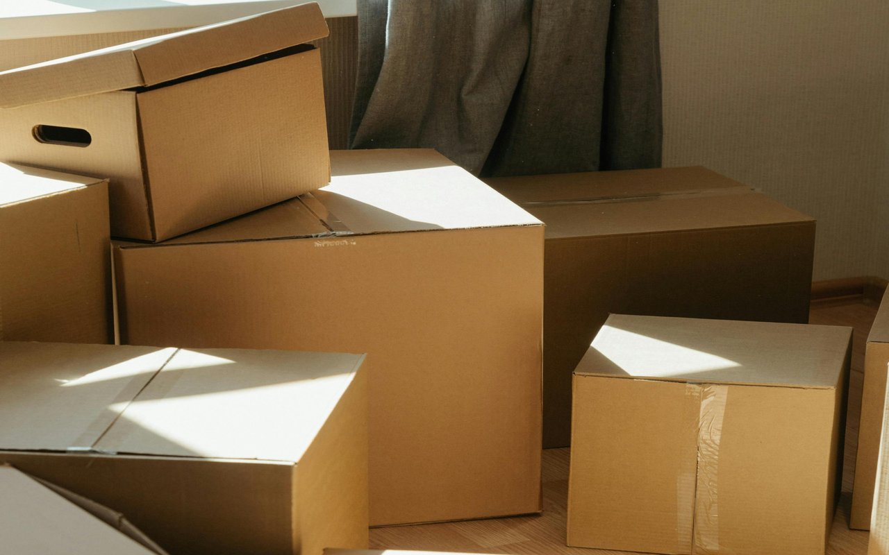 Cardboard moving boxes stacked in a sunlit room.