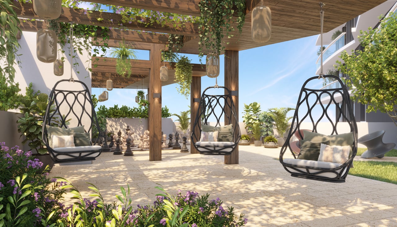 NEXO Residences terrace with hanging chairs beneath a wooden pergola and an outdoor chess set.