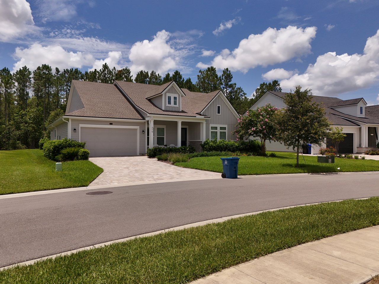 Gray gabled home with an attached garage, paved driveway, and covered front porch.