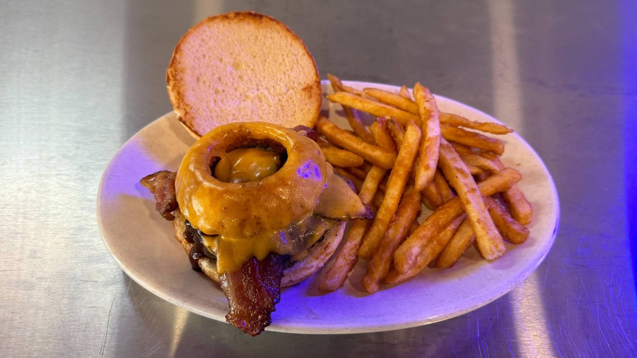 Bacon cheeseburger topped with an onion ring, served with fries.