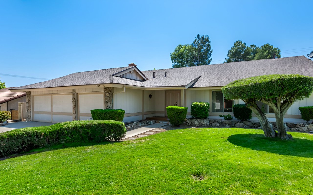 Single-story home with an attached garage, stone accents, and a broad, neatly landscaped front lawn.