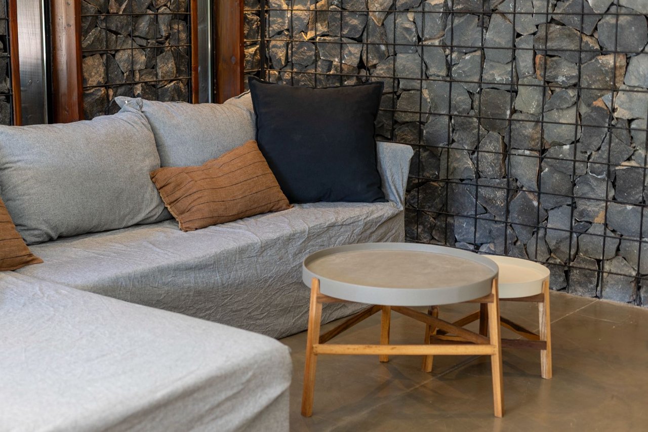 Living room with a gray sectional, nesting coffee tables, and a dark stone wall.