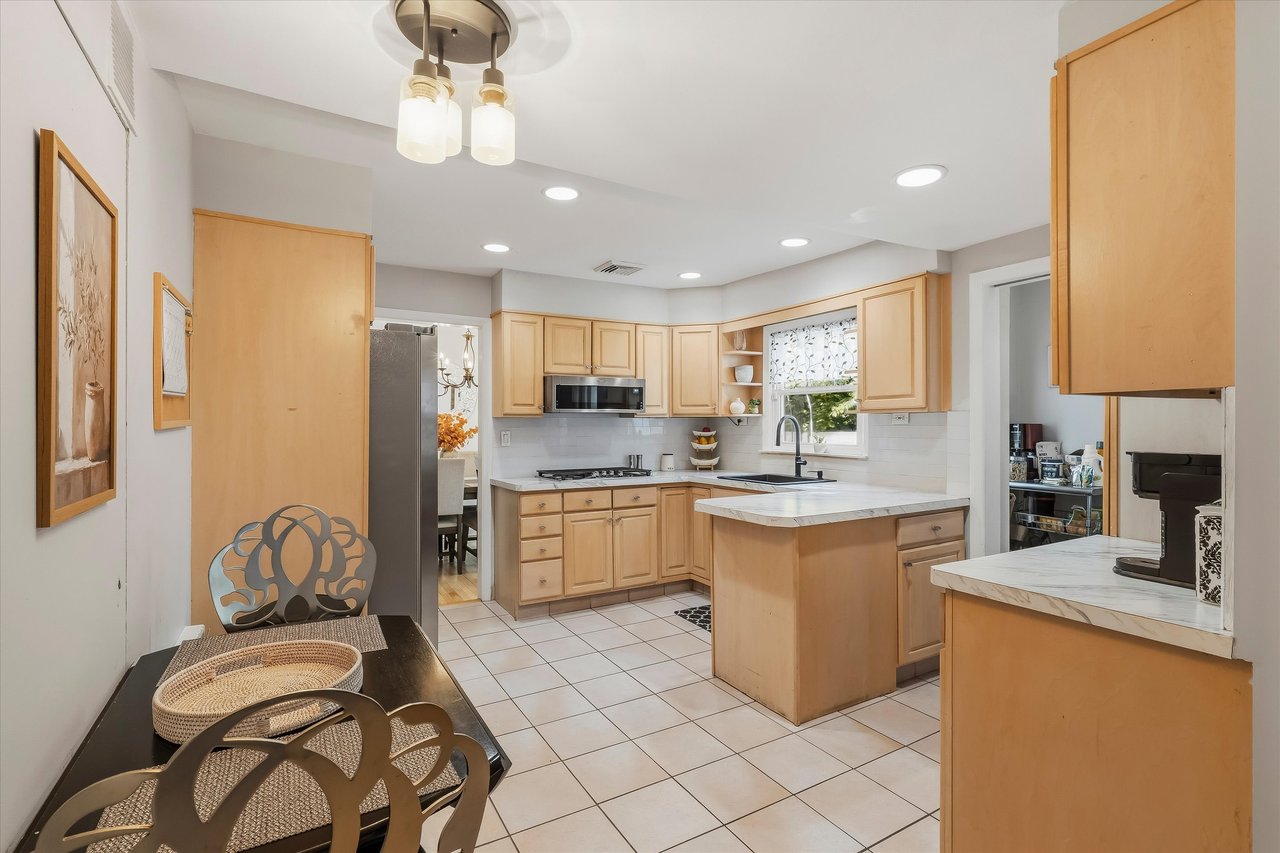 Kitchen with light wood cabinetry, a central island, stainless steel appliances, and a window above the sink.