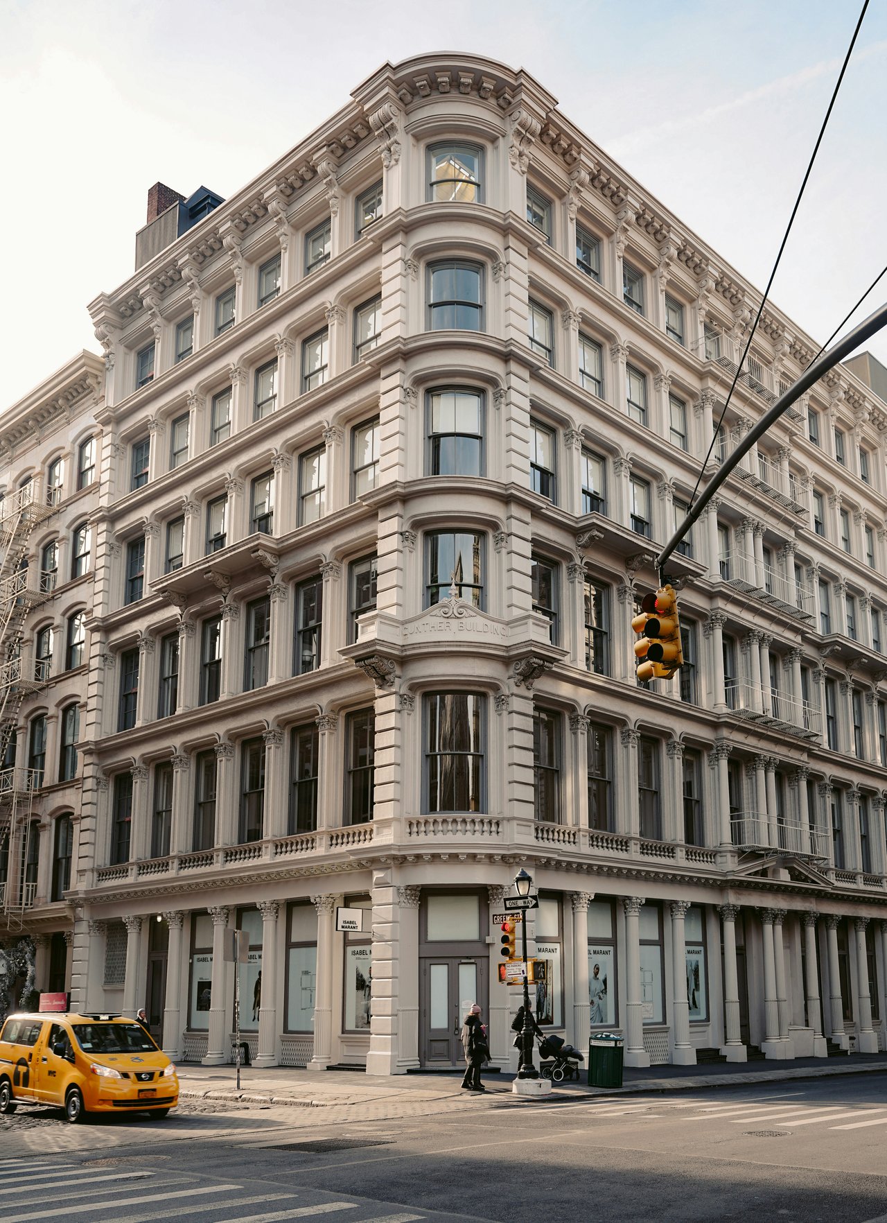 Ornate corner commercial building with a pale stone facade, tall windows, and Isabel Marant storefronts.