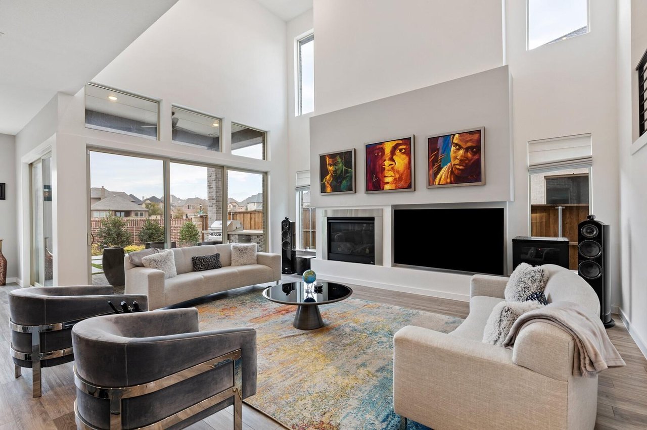 Soaring two-story living room with fireplace and floor-to-ceiling windows in a luxury home in Phillips Creek Ranch, Frisco TX.