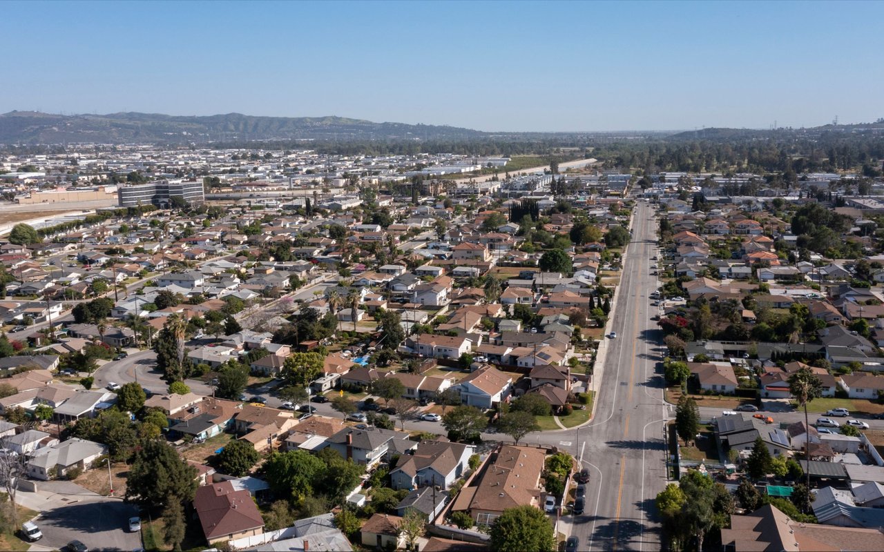 Aerial view of Rosemead homes along a broad road, with distant hills.