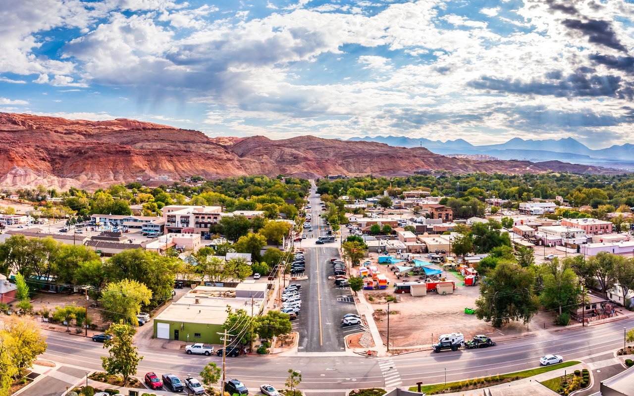 Aerial view of Old Town beneath red sandstone cliffs, with a tree-lined main street through the center.