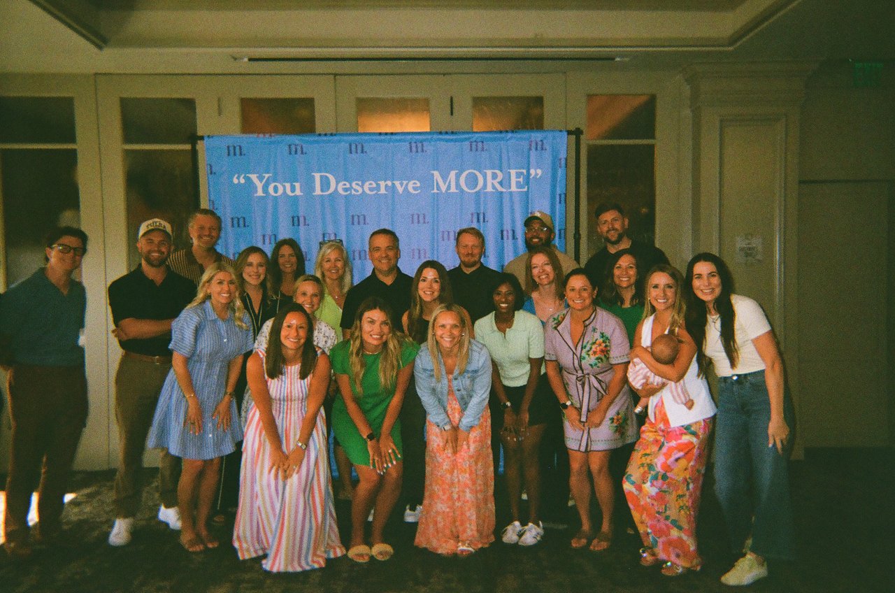 MORE Agency team posing together beneath a “You Deserve MORE” banner.