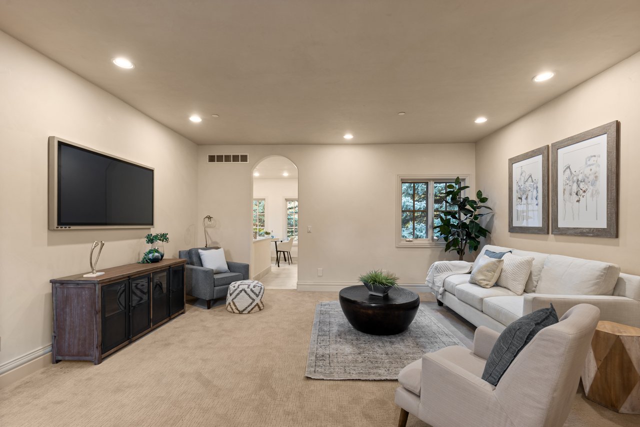 Living room with a white sofa, wall-mounted television, and round black coffee table.