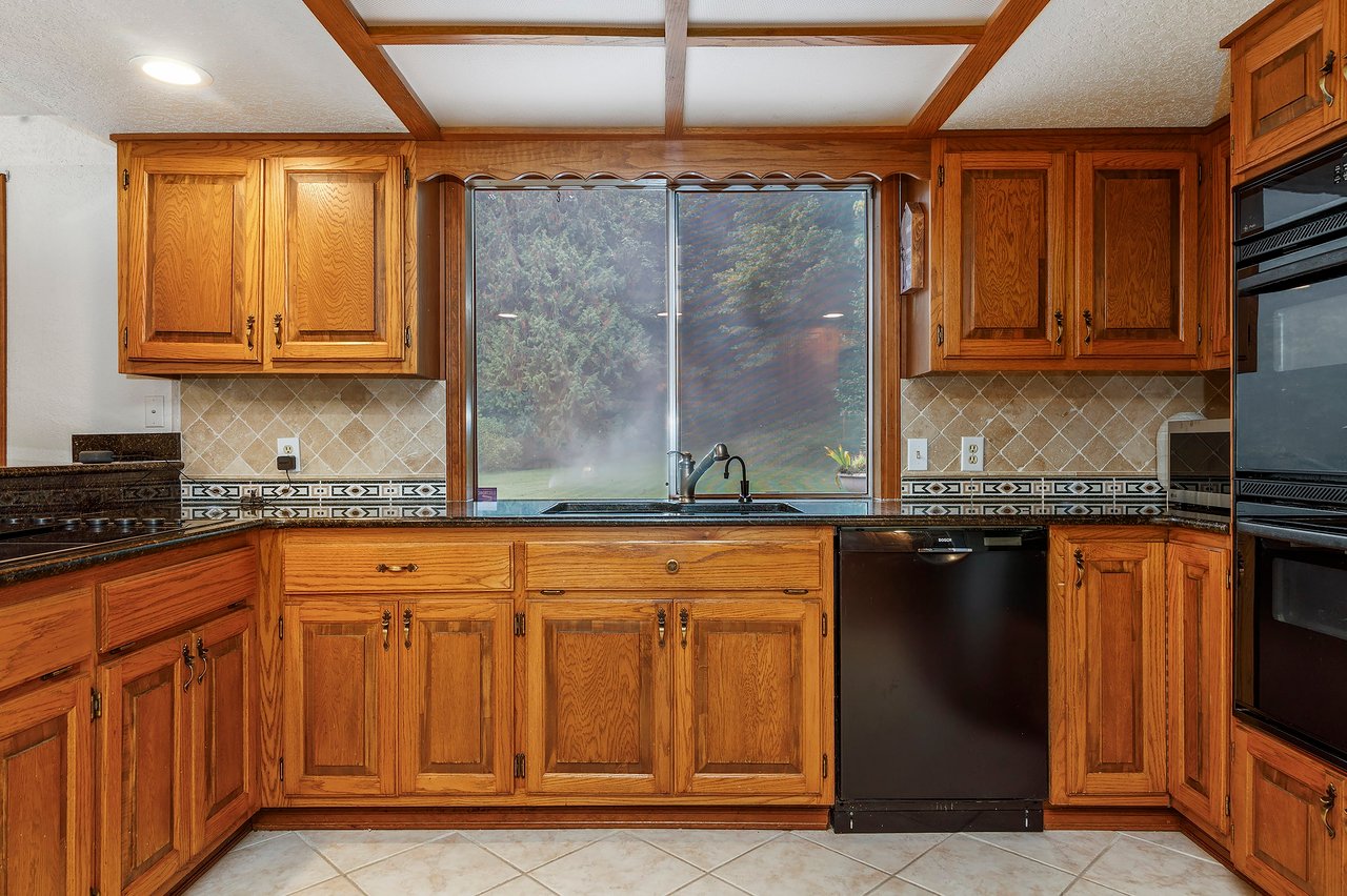 Step into the kitchen with its inviting oak cabinets, designer tile accents, and luxurious granite slab countertops—a perfect blend of style and comfort for your casual culinary moments.