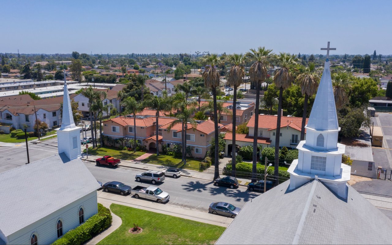 Aerial view of Pico Rivera homes and palm trees between two white church steeples.