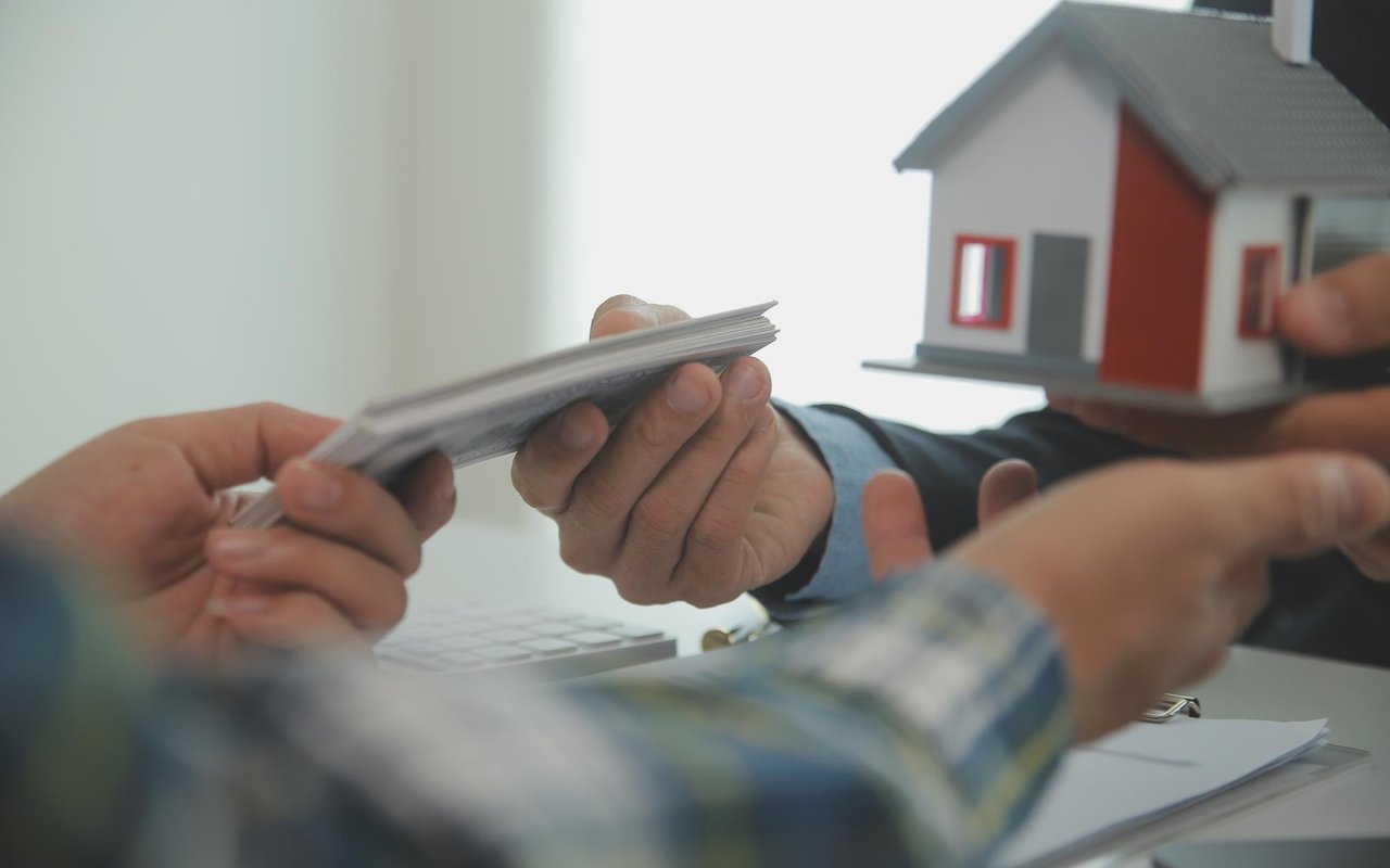 People exchange cash beside a model house during a real estate transaction.