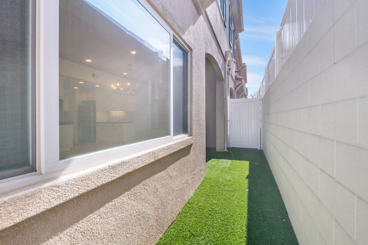 Private patio with large sliding glass doors, artificial turf, and block wall for privacy