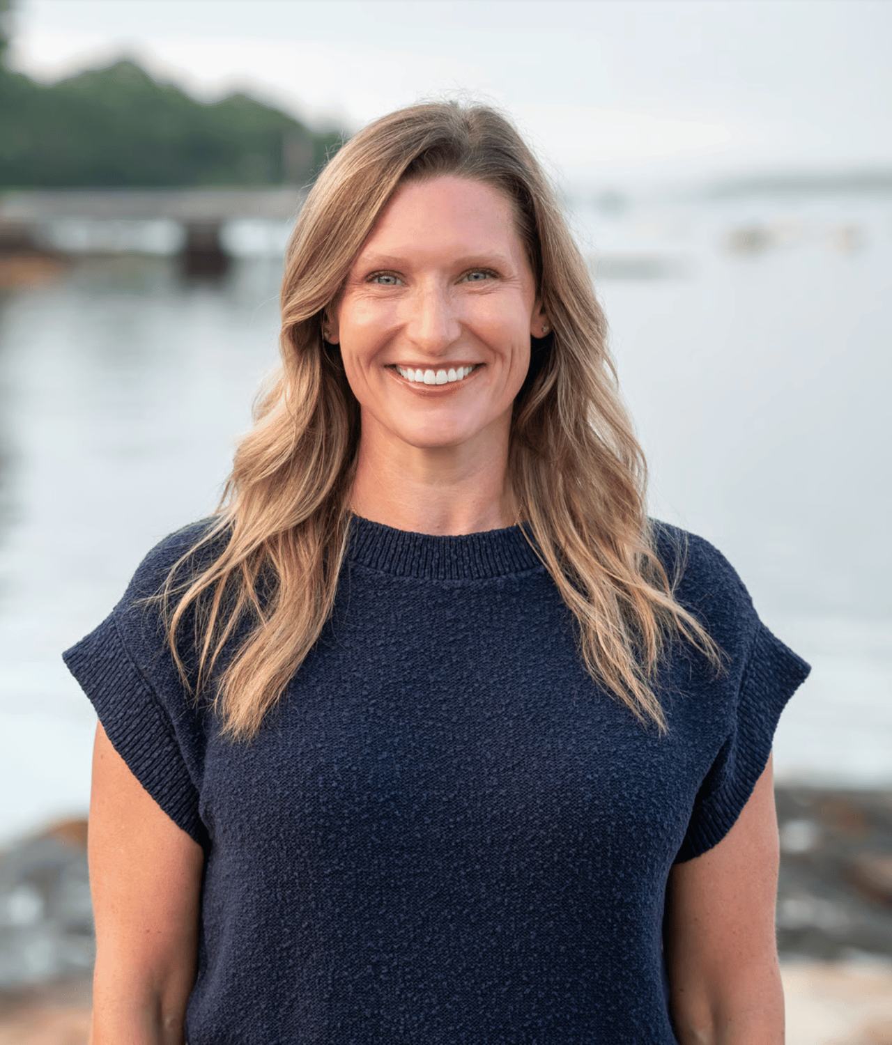 Amy Sullivan smiling in a navy sweater beside the water