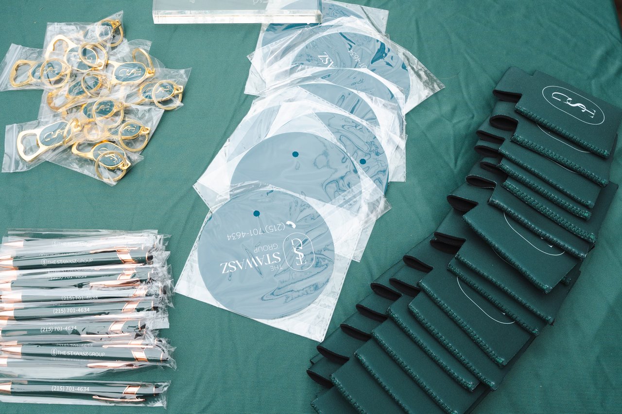 The Stawasz Group block party giveaways, including branded pens, bottle openers, round promotional items, and drink sleeves.