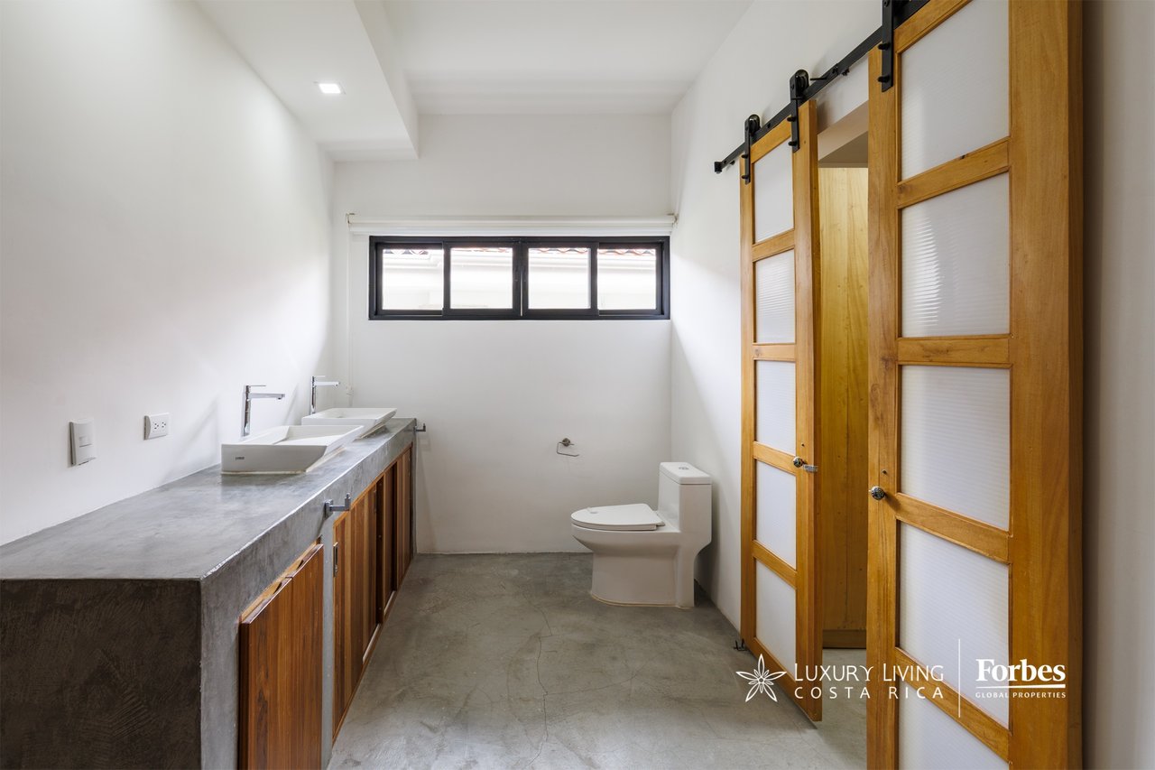 Modern bathroom with a concrete double-sink vanity and sliding wooden doors.