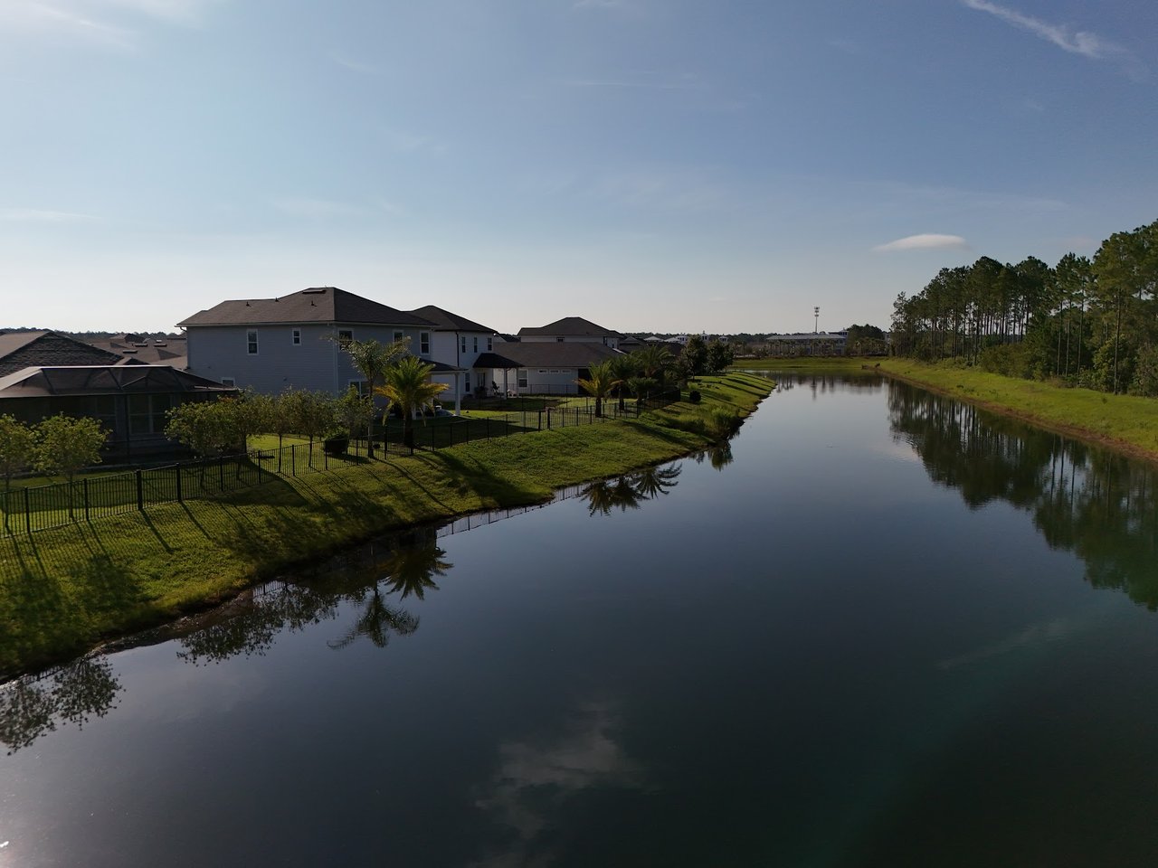 Silverleaf Village homes line a calm pond, with fenced lawns, palm trees, and pines.