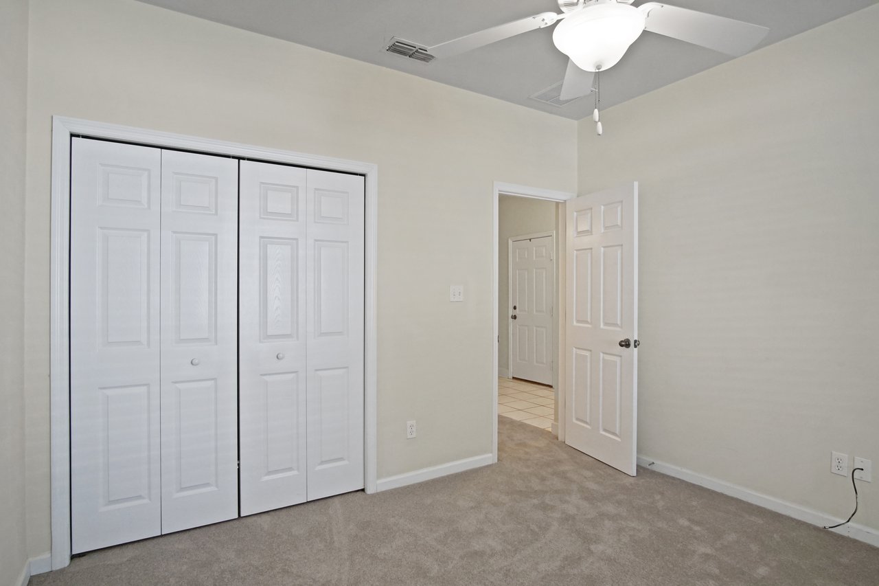 Bedroom at 5441 Hampton Hill Circle, Tallahassee, Florida 32311 featuring double closet doors, ceiling fan, and neutral carpet flooring.