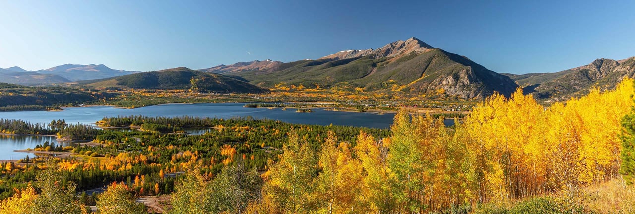 Mountain reservoir framed by golden autumn aspens and colorful forest.