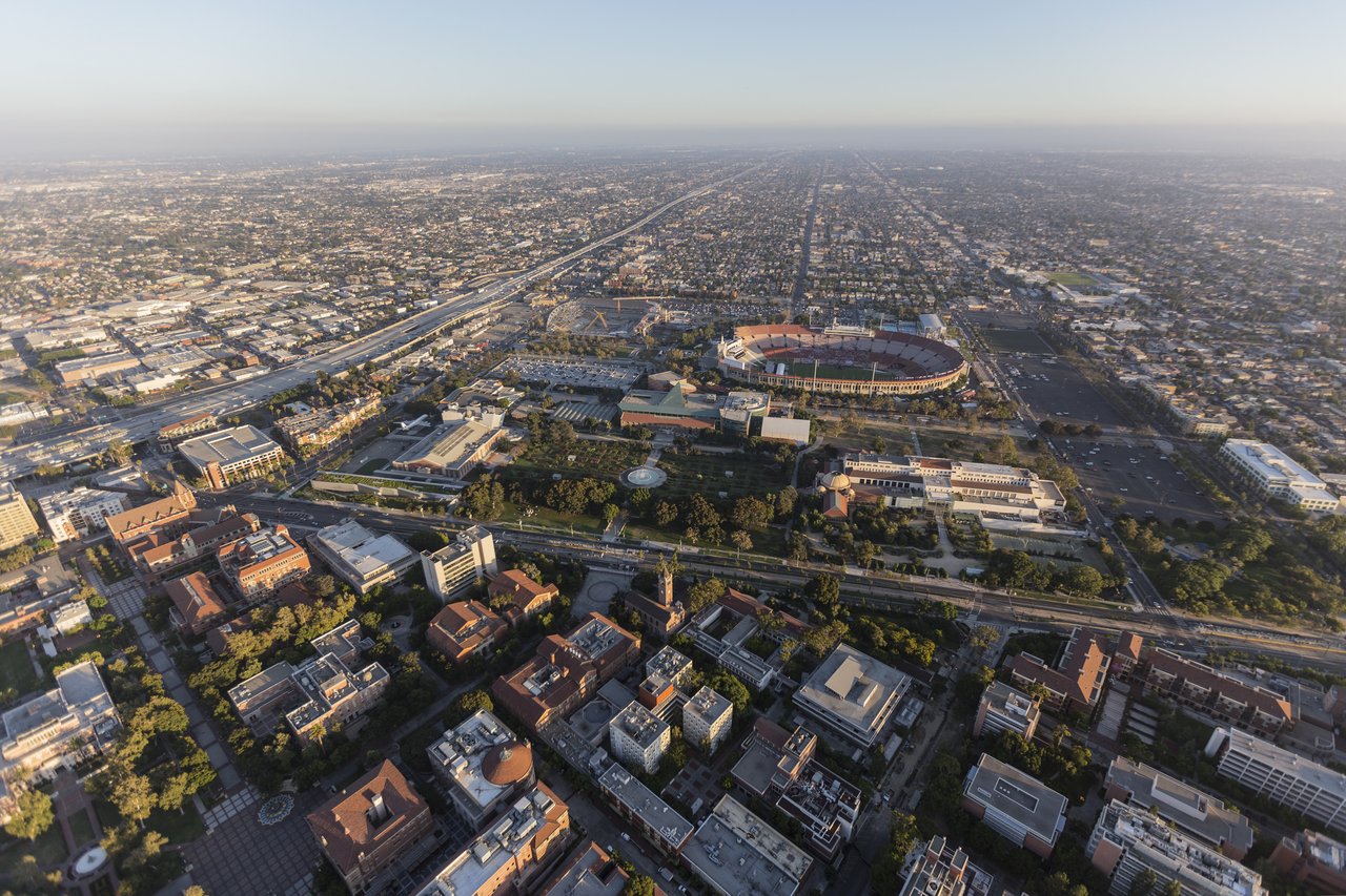 Aerial view of Exposition Park and the LA Memorial Coliseum amid the Los Angeles city grid.