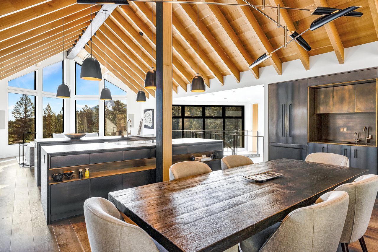 Boulder mountain home dining space with rustic table, gray chairs, and modern black cabinetry under vaulted wooden ceiling