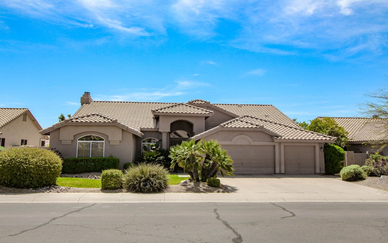 Homestead home with a tiled roof, arched entry, three-car garage, and palm landscaping.