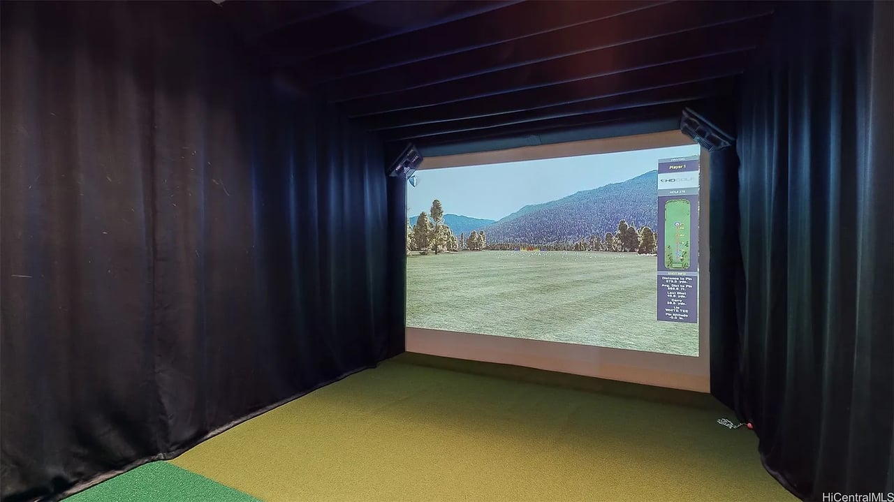 Golf simulator room with a large course projection screen and artificial turf flooring.