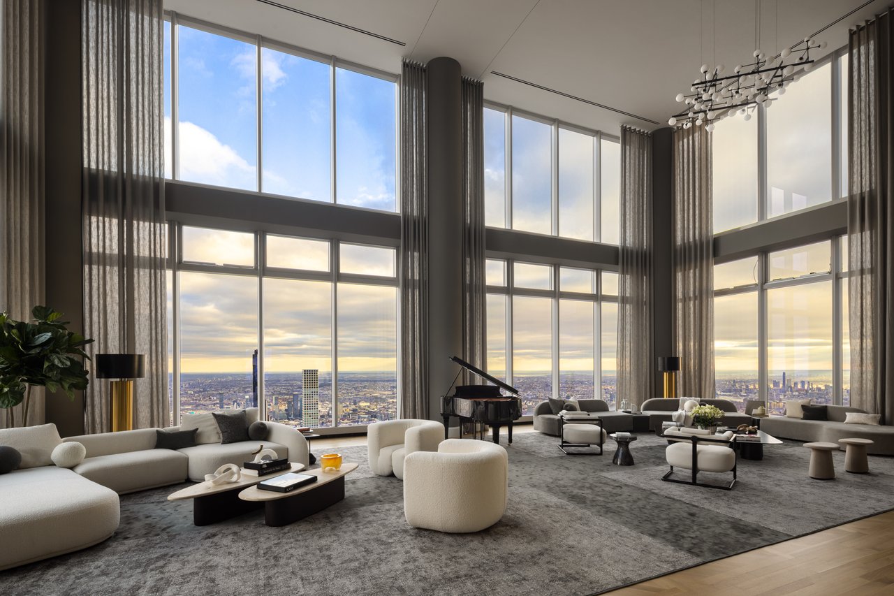 Living room with tall windows, city views, cream seating, and a grand piano.
