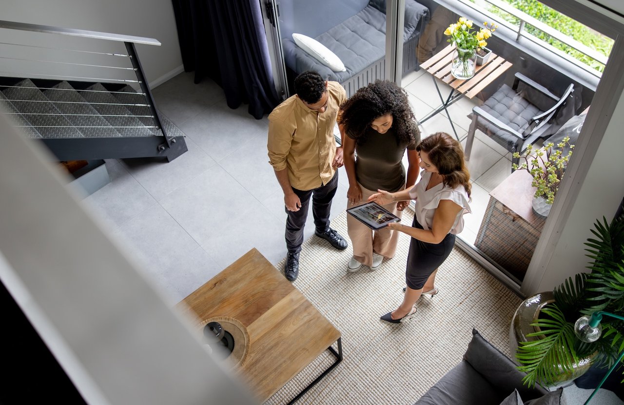 A real estate agent meeting with clients in San Francisco, discussing home buying and selling strategies in a competitive market.
